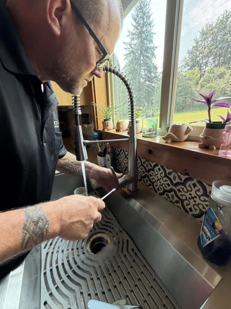 Plumber in the kitchen fixing the sink tap